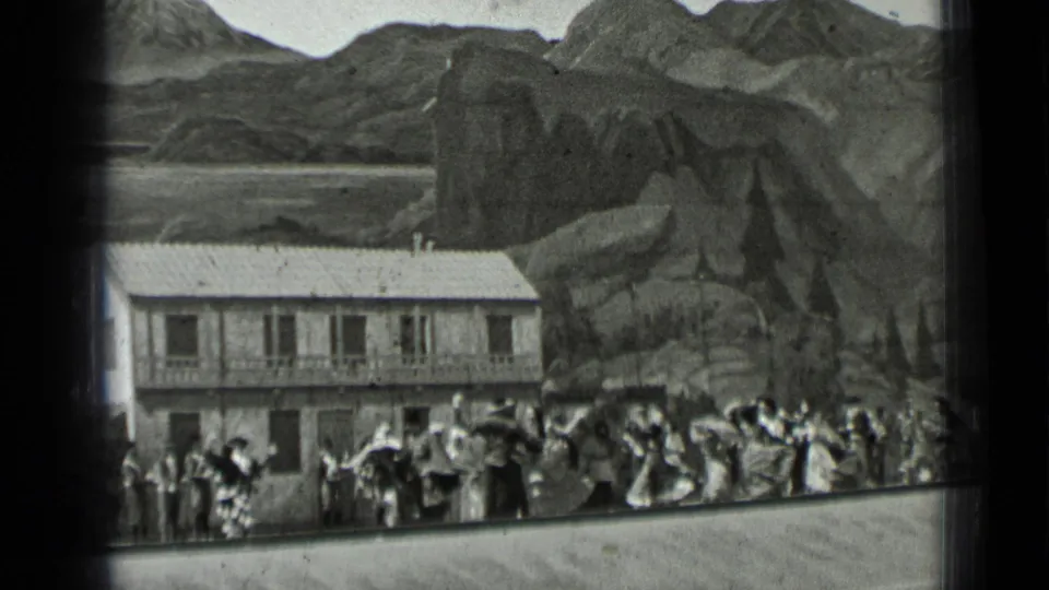 Home-movie frame from the 1937 San Francisco clip showing dancers and onlookers beside a large building.