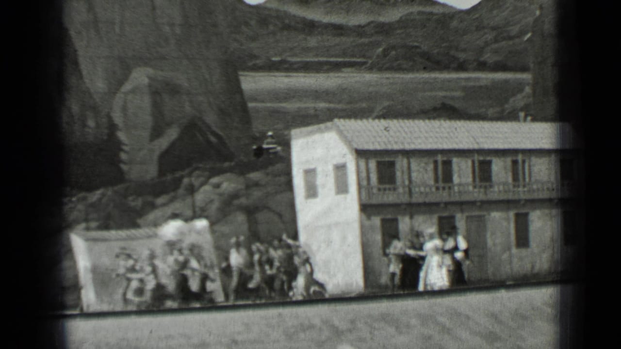 People gathered near a small facade with painted rocky scenery behind it.