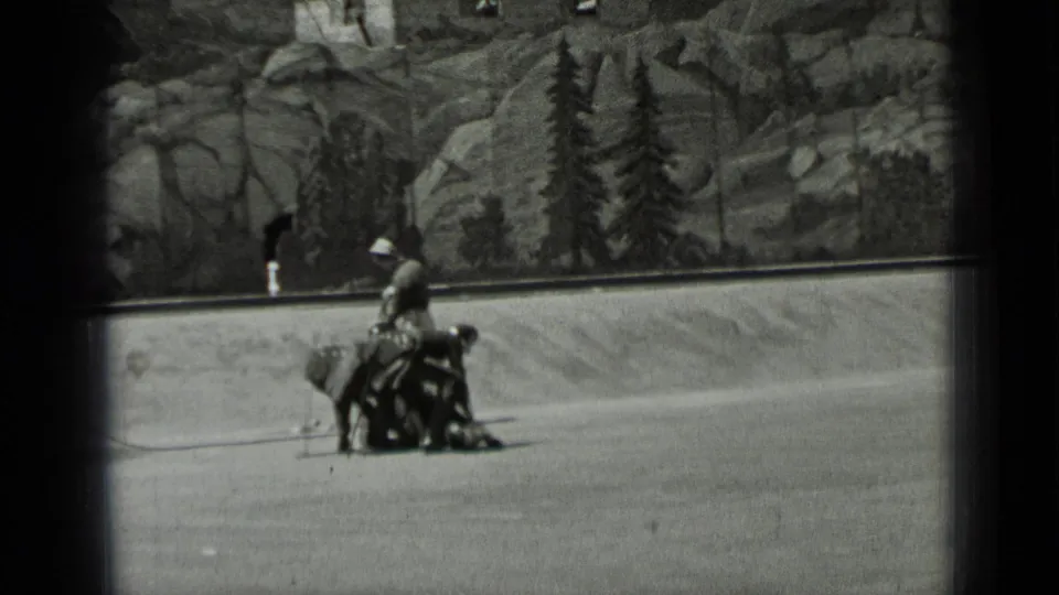 1937 San Francisco 8mm frame showing adults on open ground beside a low cart or sled-like prop.