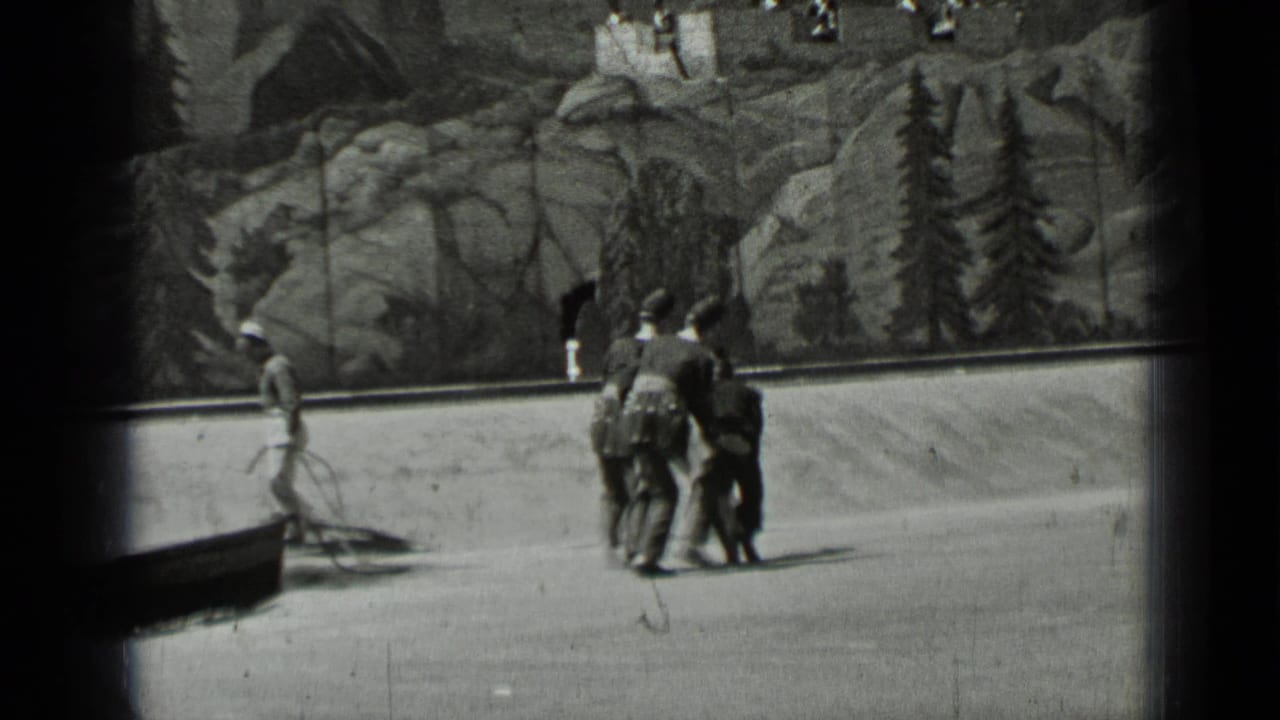Uniformed figures walk across an open area before a painted rocky landscape backdrop.