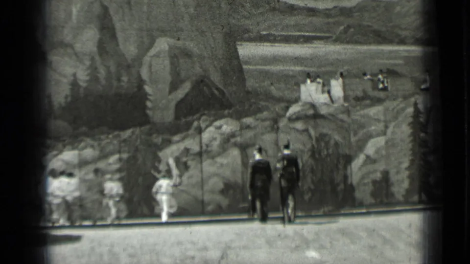 Dark-uniformed participants stand near white-clad figures in front of a painted rocky backdrop in 1937 San Francisco home-movie footage.
