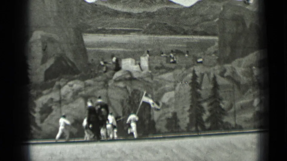 A group of dark- and white-uniformed participants gathers around a flag before a painted rocky forest backdrop in dated 1937 San Francisco footage.