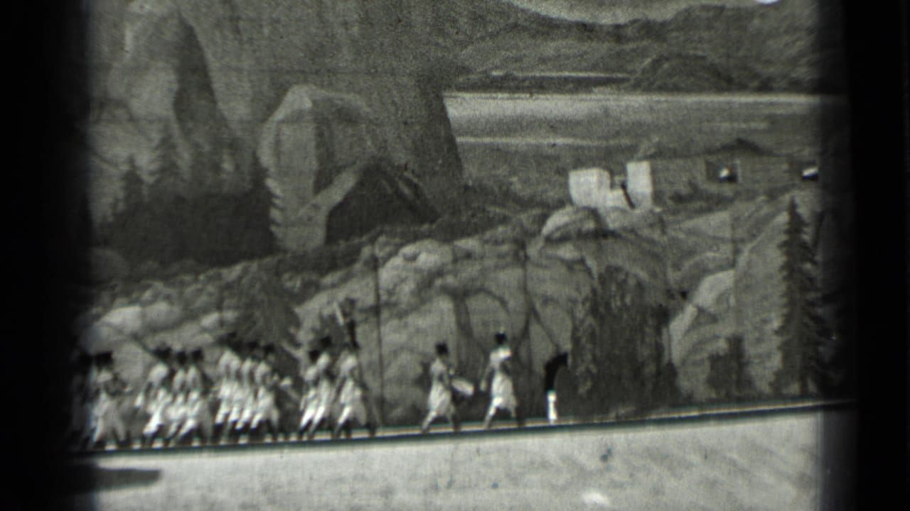 A line of uniformed marchers continues along the road in front of scenery.