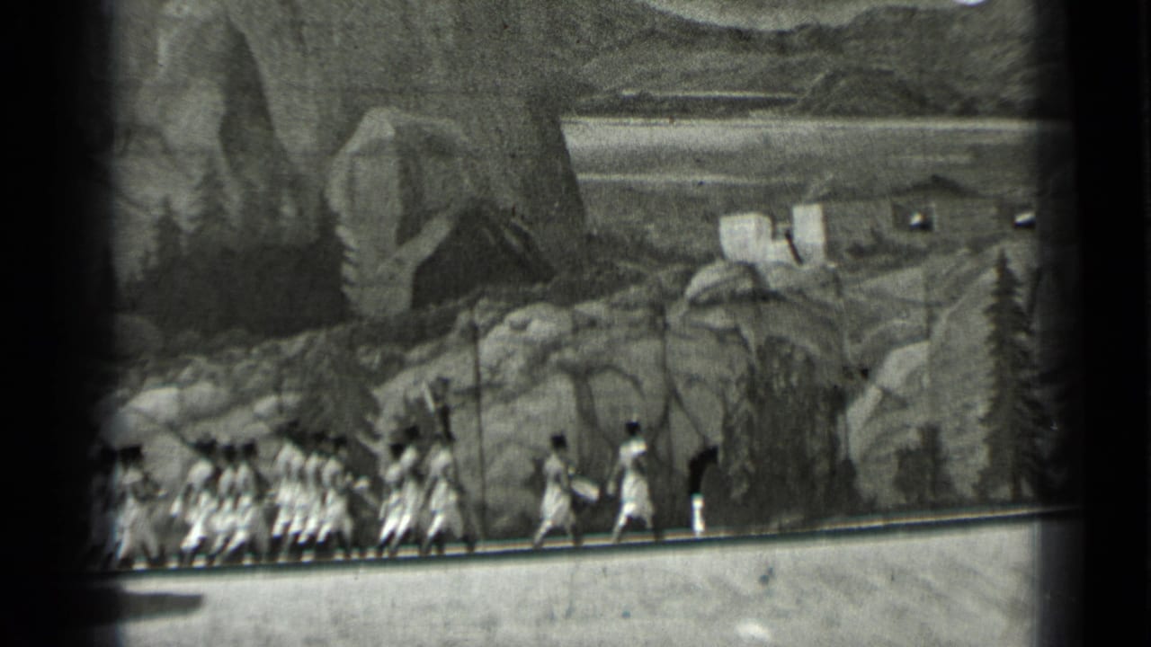 Women in light dresses run in a line beside a painted mountain backdrop.