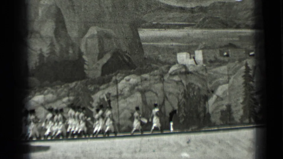 The final visible frame keeps the women low in the scene, with painted mountains, rocks, and a cabin-like shape behind them.