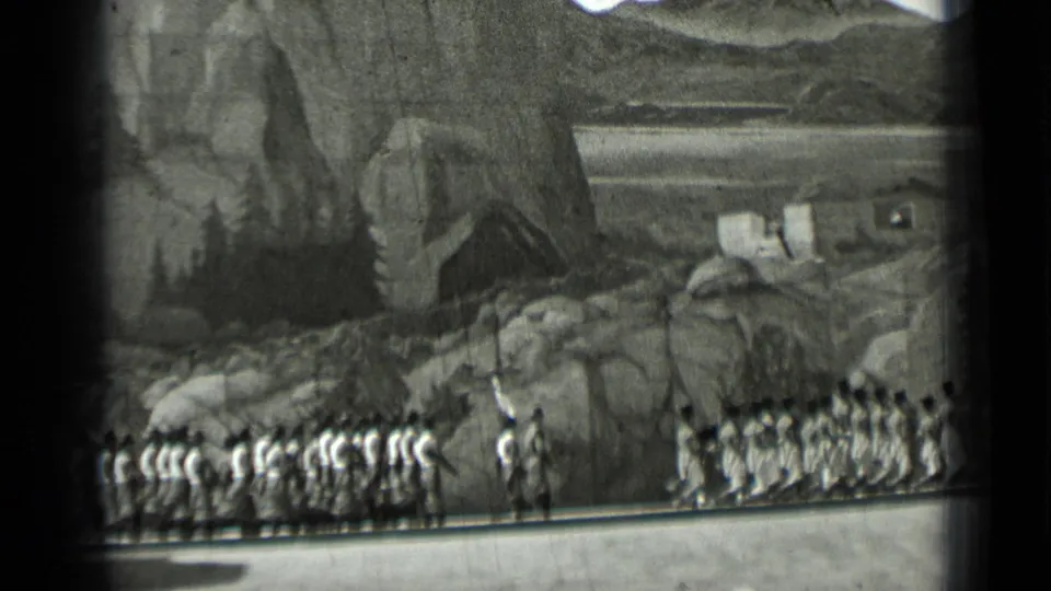 1937 San Francisco home-movie frame showing uniformed marchers passing a rocky scenic backdrop, seen from a distant spectator viewpoint.