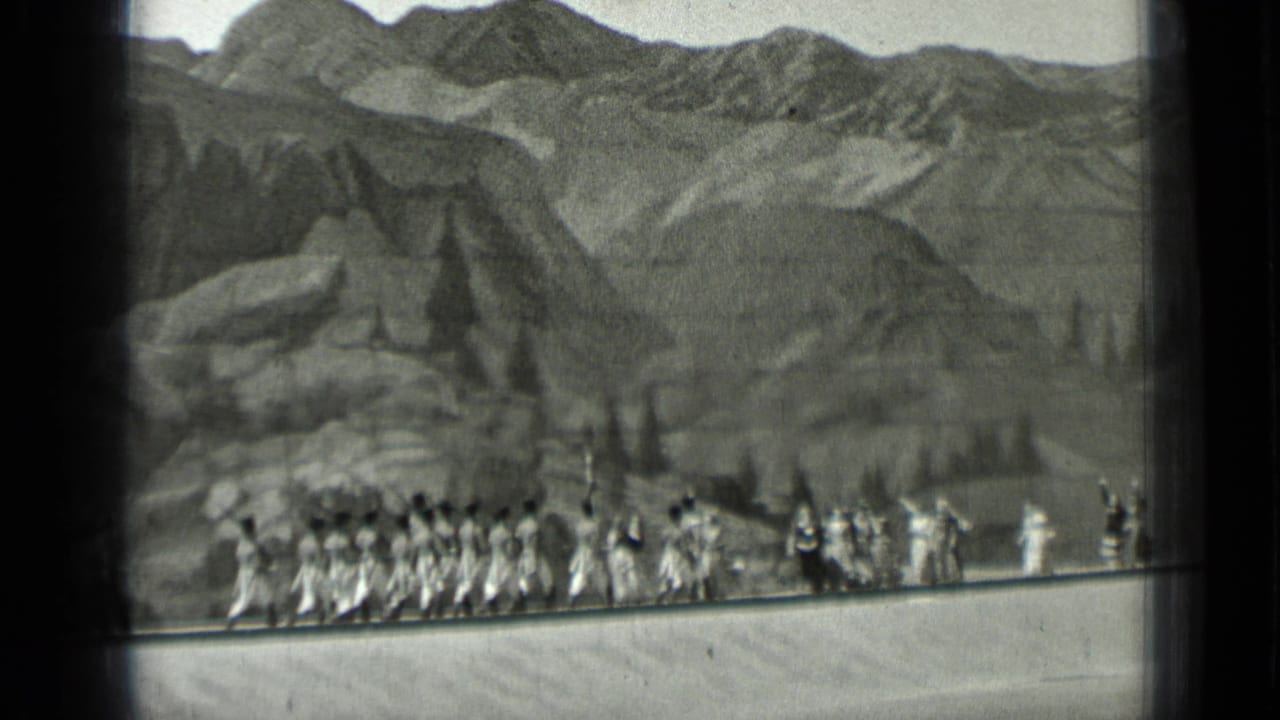 Costumed performers march in formation before a painted mountain backdrop.
