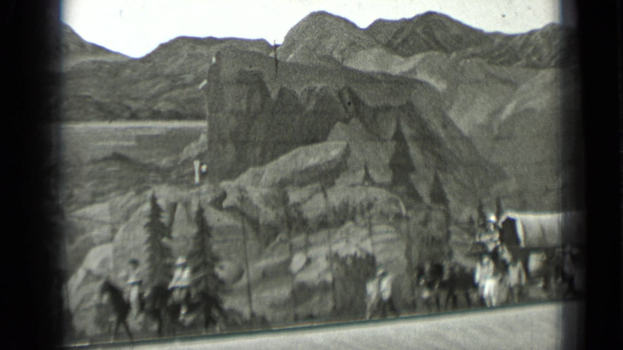 Painted mountains and rocky scenic flats with covered wagons at the edge.