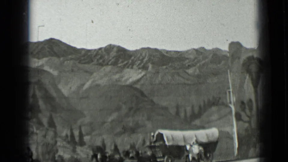 1937 San Francisco 8mm frame showing a covered wagon before a painted frontier mountain backdrop.