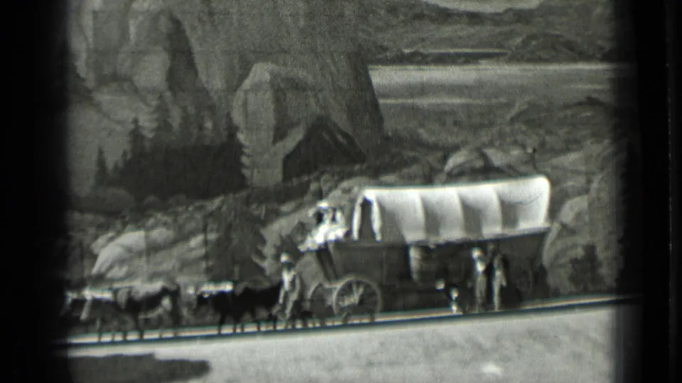 Final 1937 8mm frame shows the wagon display from the side, with animals in front, figures near the wagon, and painted mountains behind.