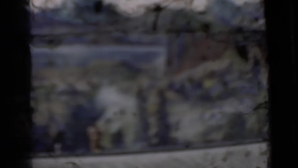 Soft exposed 8mm frame from the San Francisco clip, with indistinct figures and scenic painted landscape visible.