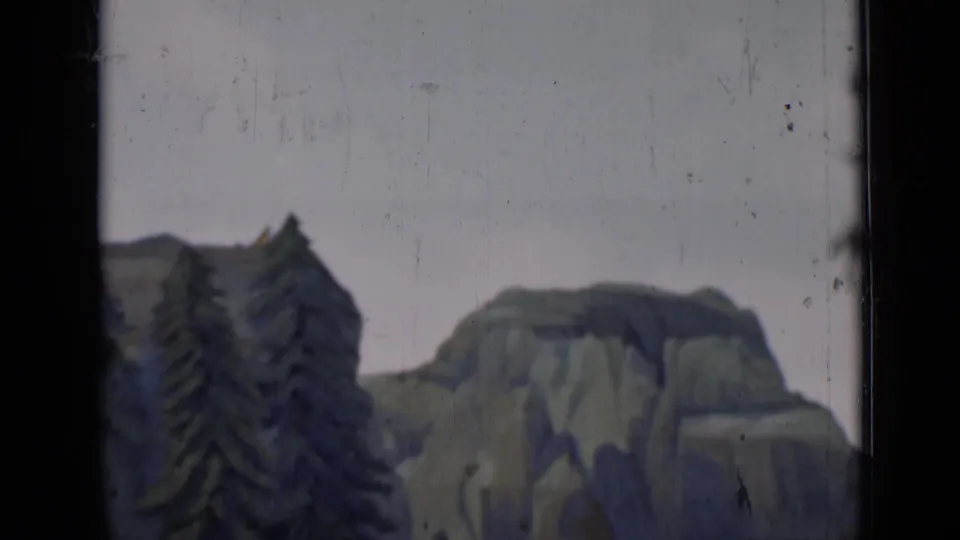 1937 San Francisco home-movie frame showing a painted mountain backdrop with dark evergreen trees and visible film gate edges.
