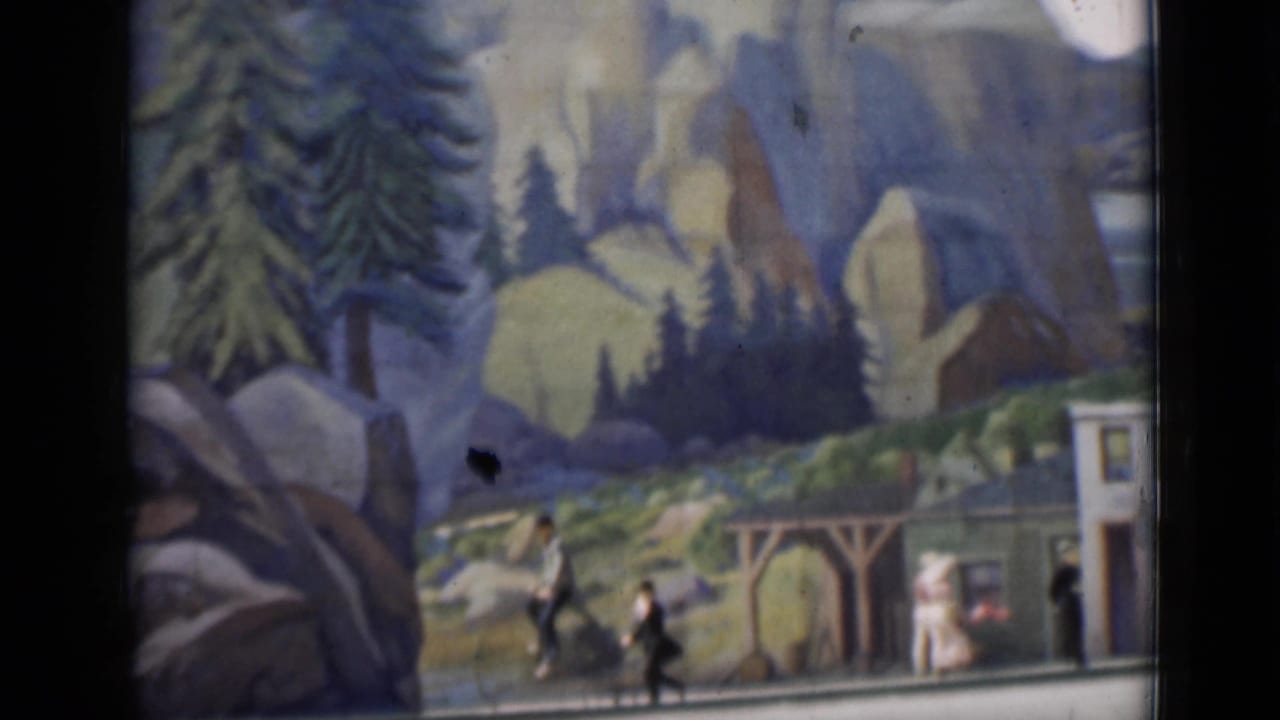 1937 San Francisco-associated 8mm frame showing a miniature town display with painted mountains, storefront facades, and small figures.