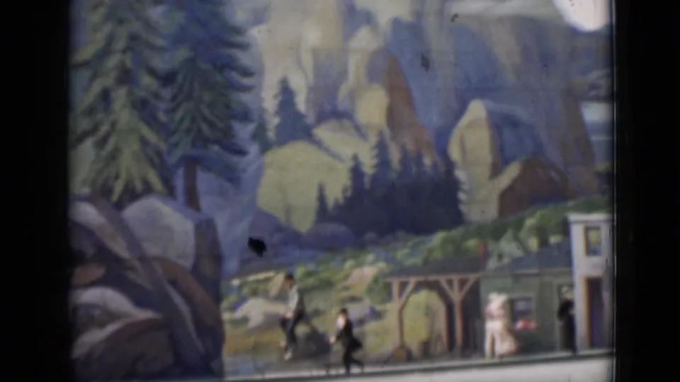 1937 San Francisco-associated 8mm frame showing a miniature town display with painted mountains, storefront facades, and small figures.