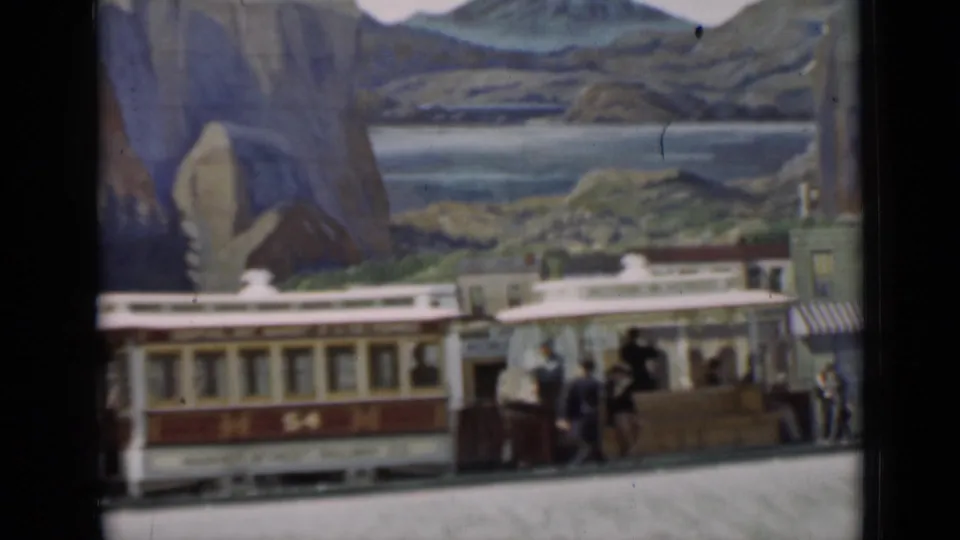 Red-and-cream trolley marked 54 moves through the miniature town scene in San Francisco-associated 1937 8mm footage.