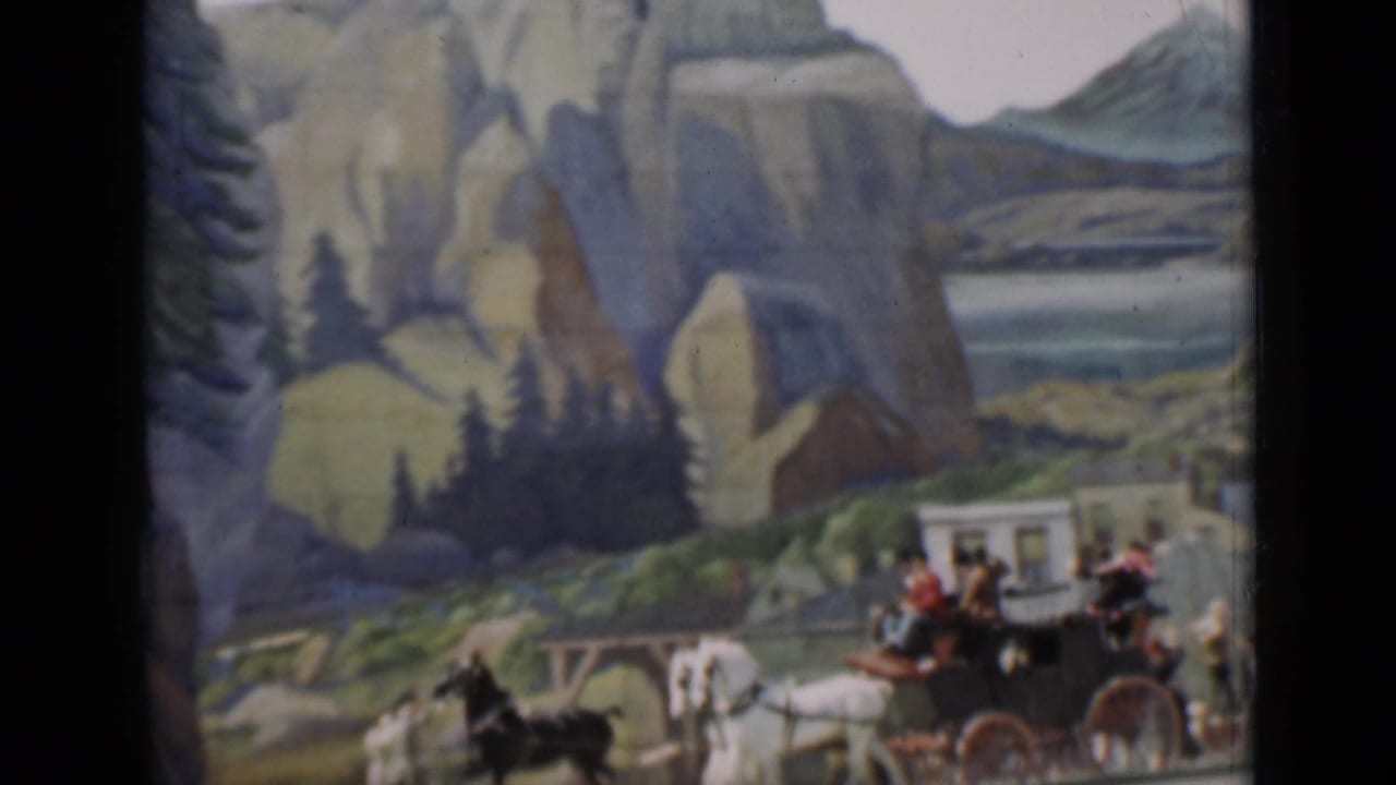 Horse-drawn carriage passes in front of a painted mountain and pine-tree set.