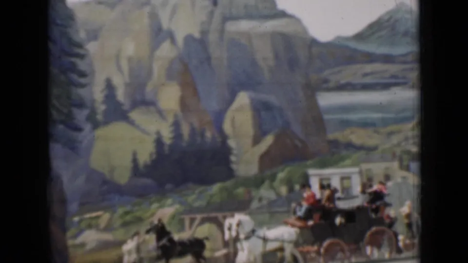 1937 8mm frame of a horse-drawn carriage moving across a staged set with painted mountains, pine trees, and small scenery details.