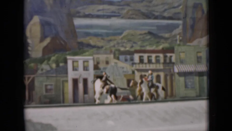1937 San Francisco 8mm frame with miniature mounted figures near painted storefronts and scenic mountains.