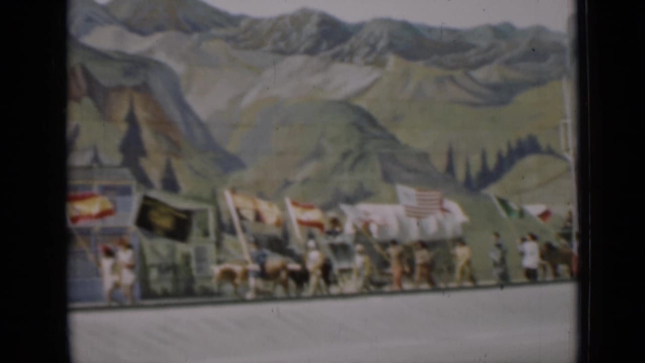 1937 San Francisco parade view with covered wagons, horses, flags, and walkers in front of a scenic backdrop.