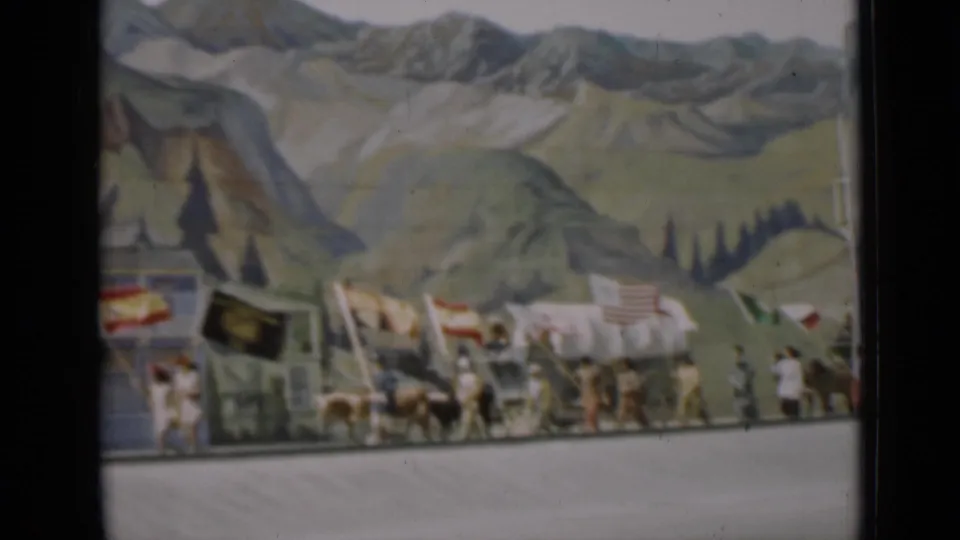 1937 San Francisco parade view with covered wagons, horses, flags, and walkers in front of a scenic backdrop.