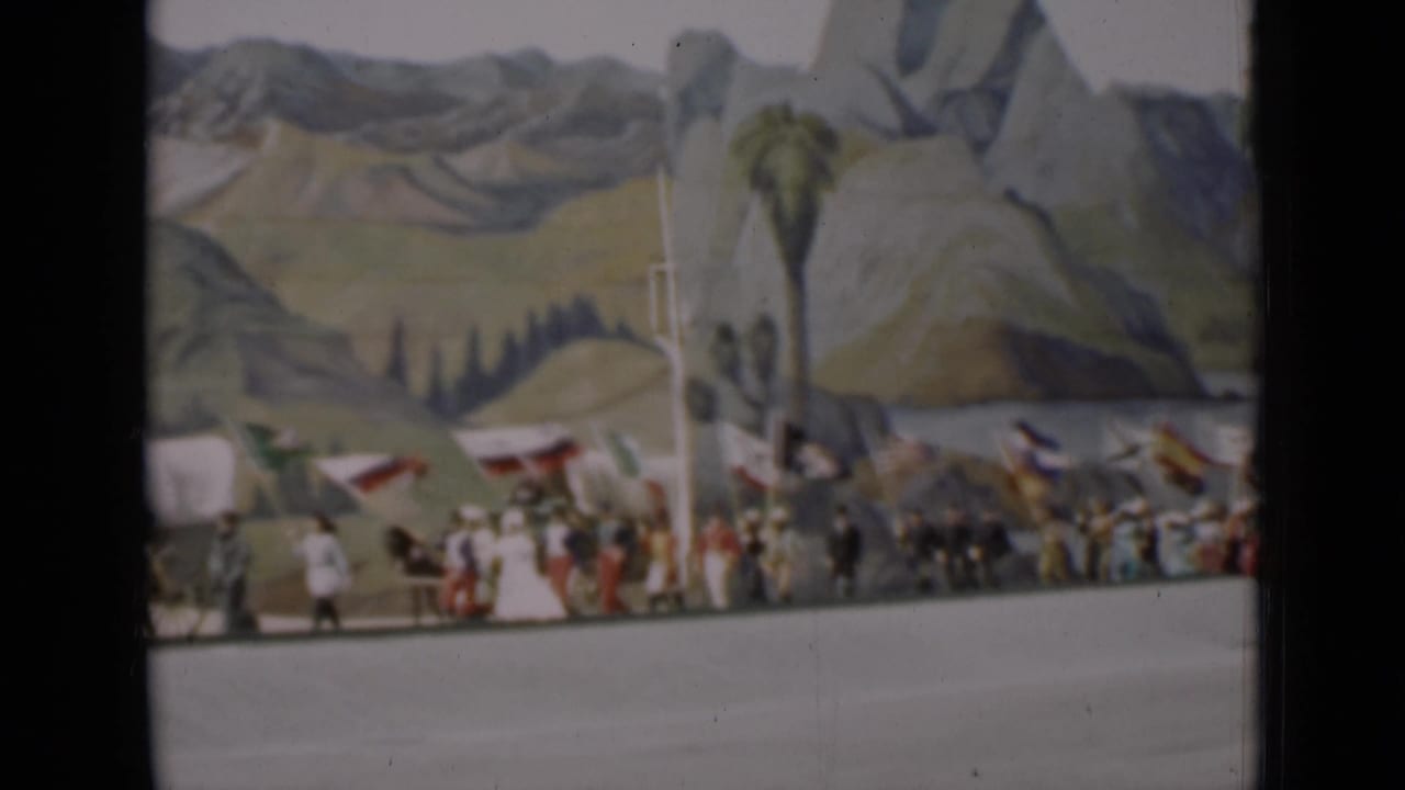 1937 San Francisco parade scene with marchers, flags, wagons, horses, and a mountain-and-tree painted backdrop.