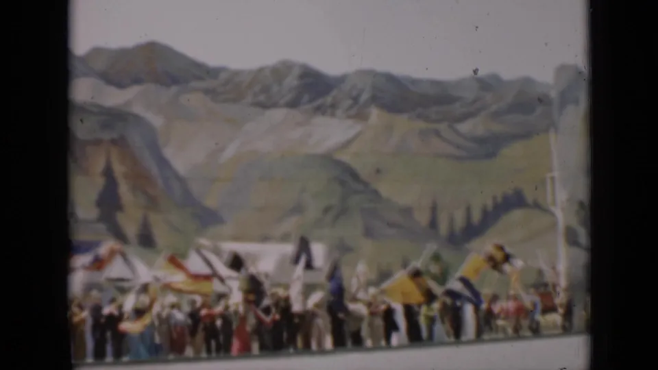 A line of people with flags stretches across a painted mountain backdrop in the 1937 San Francisco home-movie clip.