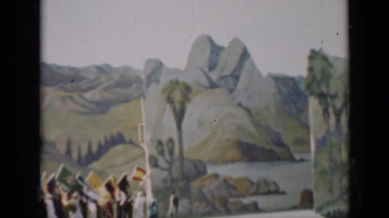 Painted mountain backdrop with flags and spectators at the lower left.