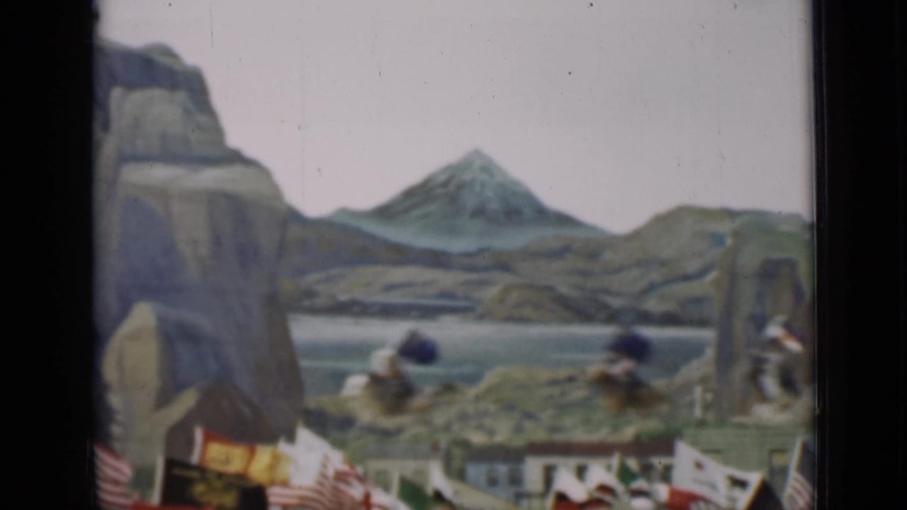 Horseback riders move across a staged scenic setting as flags fill the foreground in this 1937 San Francisco home movie.