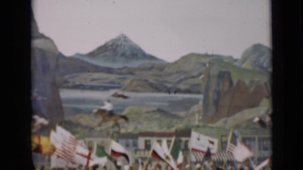 A soft 8mm frame shows flags, spectators, and horseback movement before a painted mountain backdrop in San Francisco, 1937.