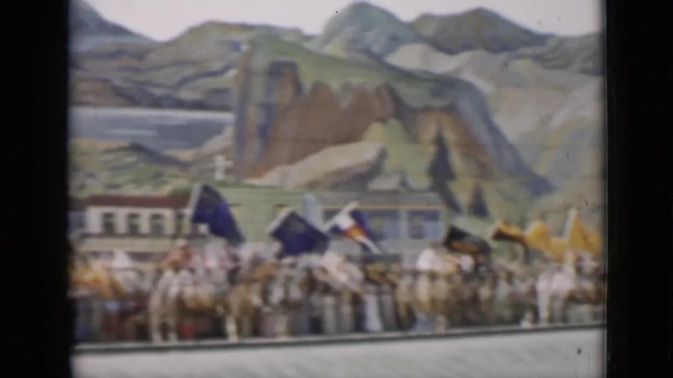 1937 San Francisco 8mm frame showing mounted riders with flags in front of a painted mountain and town backdrop.