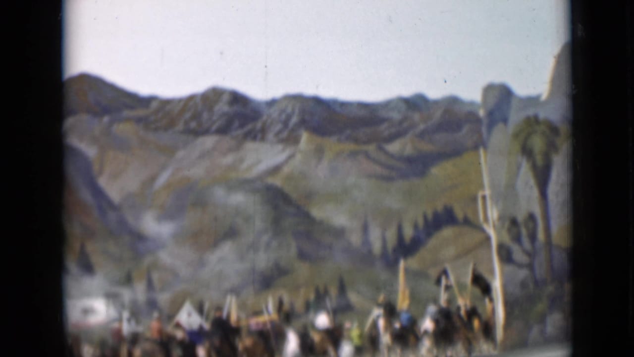 Crowd and riders appear partly blurred in front of a painted landscape backdrop.