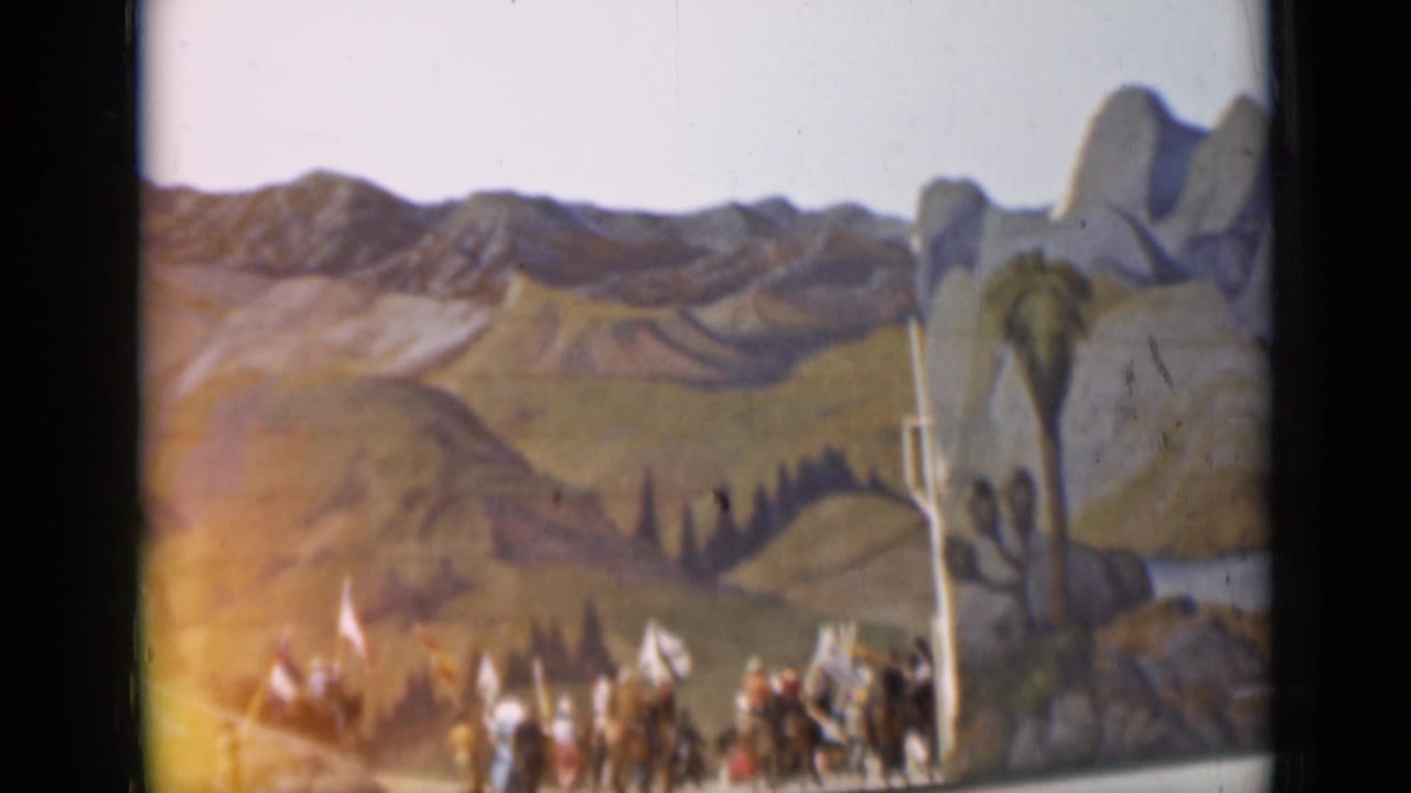 Painted mountain backdrop above a crowd of visitors in hats.