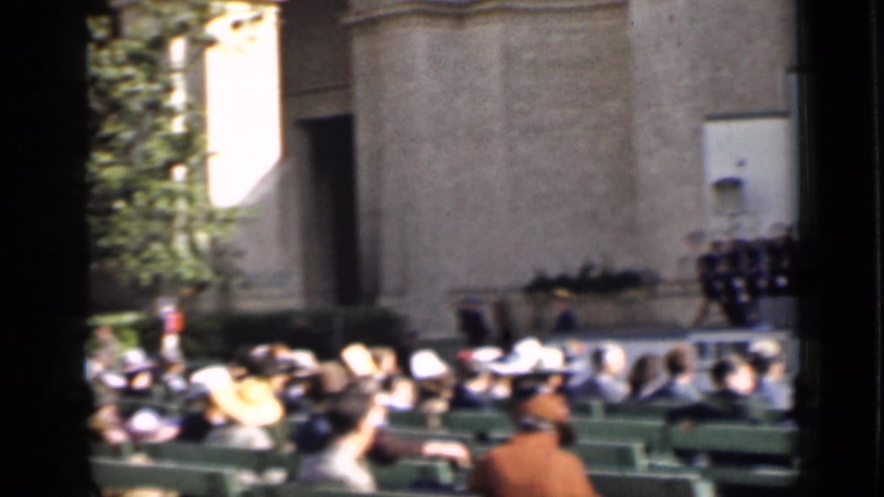 The home-movie view shifts toward the audience area, showing benches, hats, arena walls, and a partial view of the band.