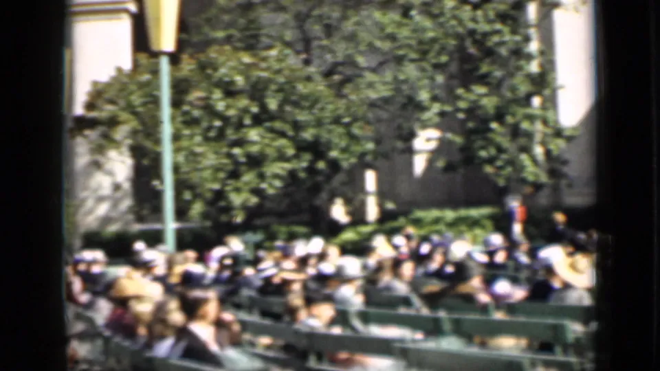 A wider 1937 San Francisco audience view shows spectators on green benches, trees, a lamppost, and the outdoor arena setting.