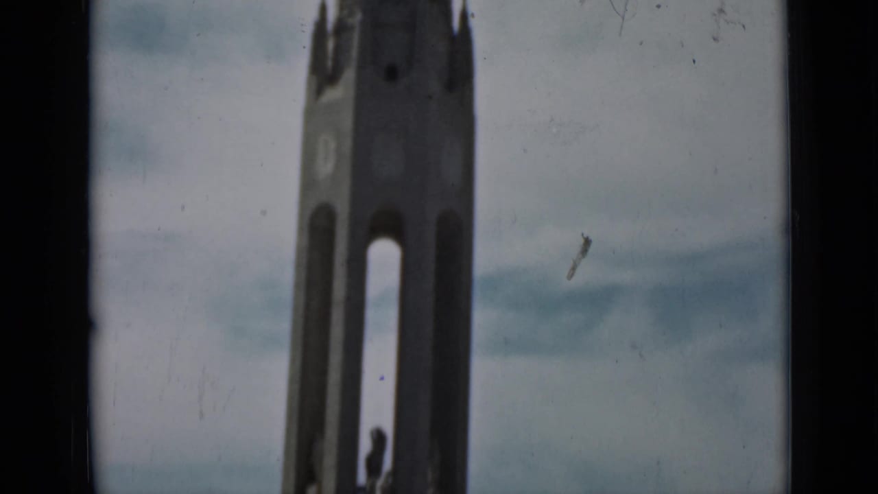 Soft view of a tall tower with arched openings against a cloudy sky.