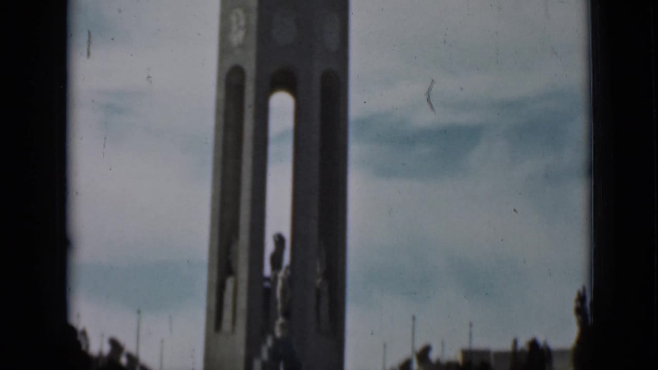 1937 San Francisco frame with the monument tower, central statue, low landscaping, and cloudy sky.