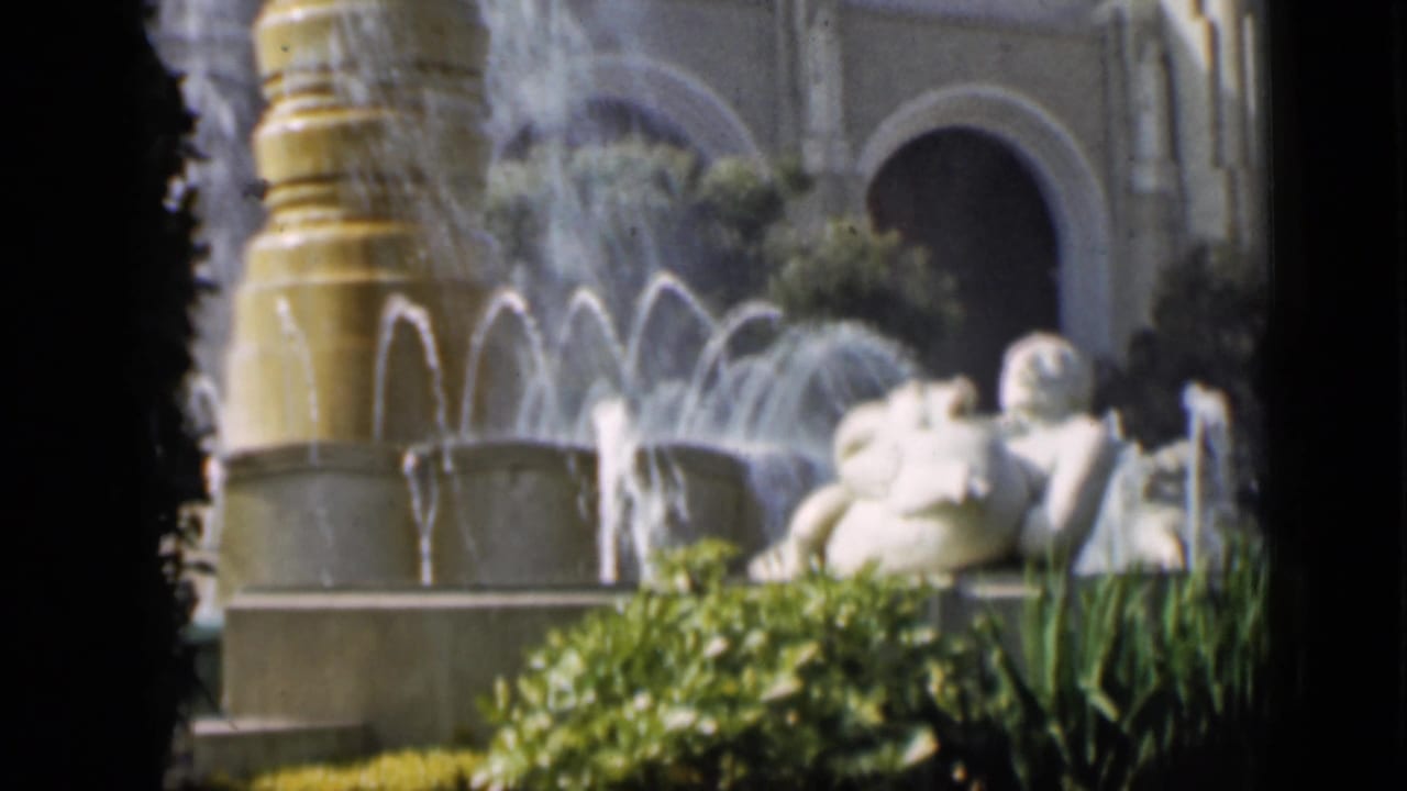 1937 San Francisco garden frame showing a large fountain, spray patterns, classical reclining figures, hedges, and arched architecture.