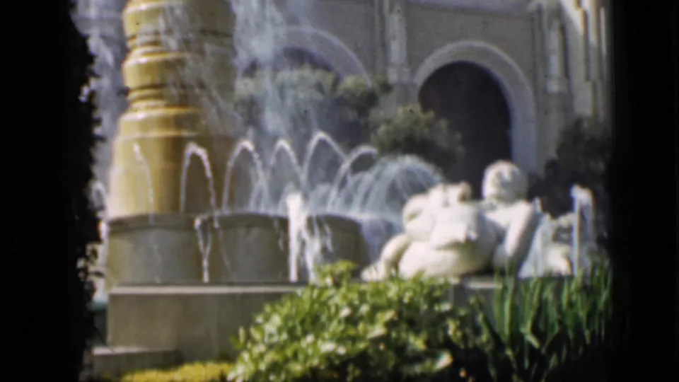 1937 San Francisco garden frame showing a large fountain, spray patterns, classical reclining figures, hedges, and arched architecture.