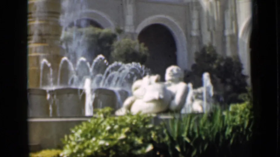 1937 San Francisco home-movie frame showing a tiered fountain, white sculpture, arched architecture, and landscaped plantings.