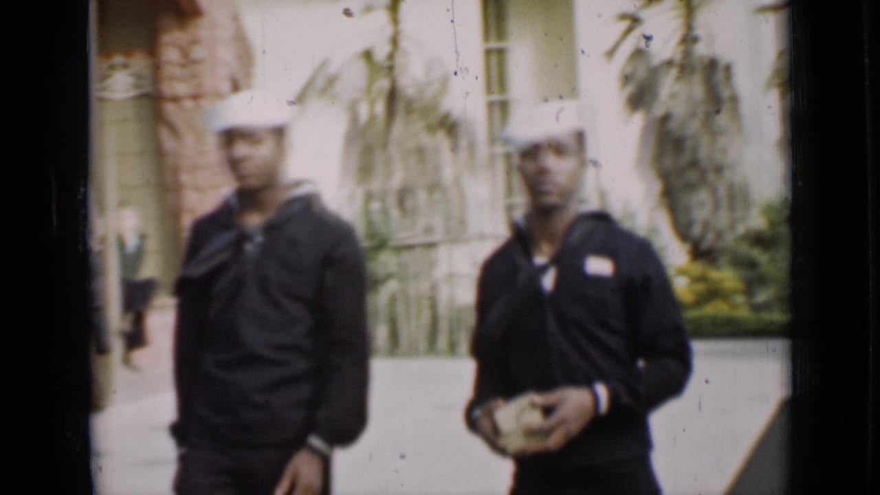 Two U.S. Navy sailors appear near a light building and planting in the 1937 San Francisco home-movie scene.