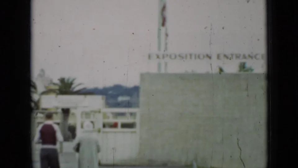 A 1937 San Francisco home-movie frame shows visitors near a concrete wall beneath the "EXPOSITION ENTRANCE" sign.