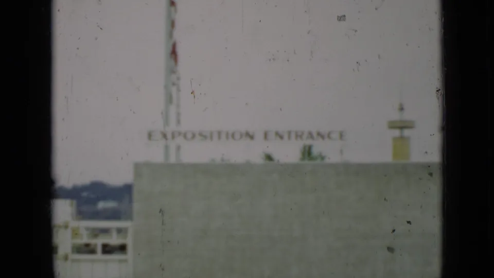 1937 San Francisco home-movie frame showing a pale building facade and an Exposition Entrance sign in soft focus.