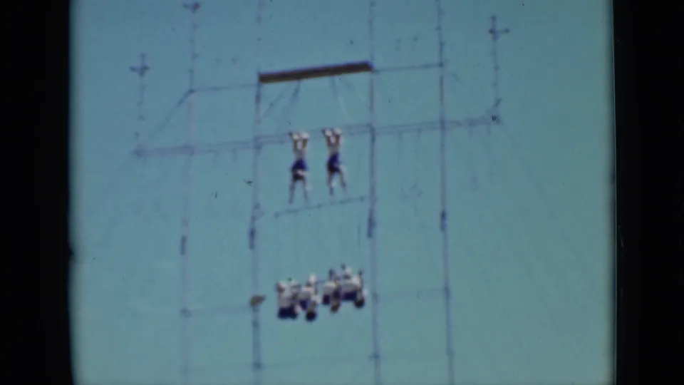 1937 San Francisco home-movie frame showing two acrobats on upper ropes above a small hanging formation.