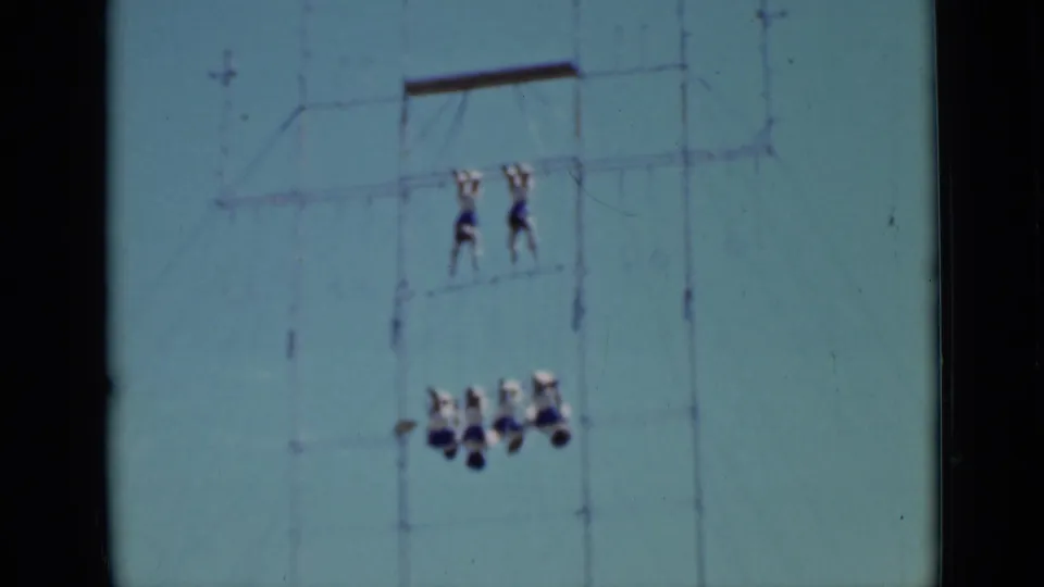Distant 1937 San Francisco frame with two upper acrobats and a lower group suspended from outdoor rigging.