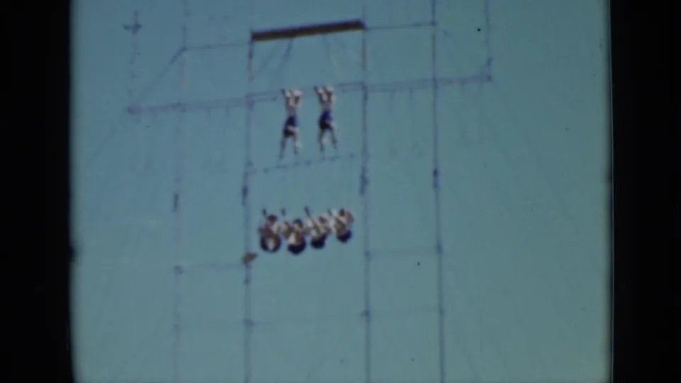 1937 San Francisco 8mm frame showing two acrobats on an upper bar and a group suspended below on a metal rig.