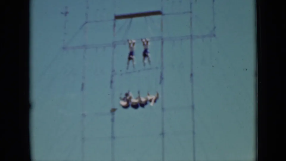 1937 San Francisco 8mm frame with four acrobats swinging in formation below two performers holding an upper bar.