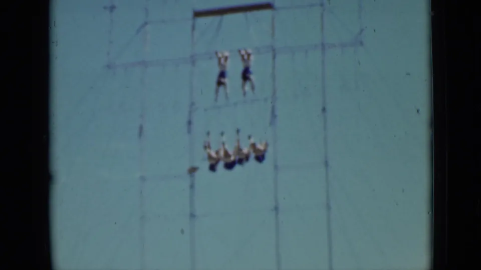 1937 San Francisco 8mm frame showing a synchronized aerial swing with performers high on a metal rig against open sky.
