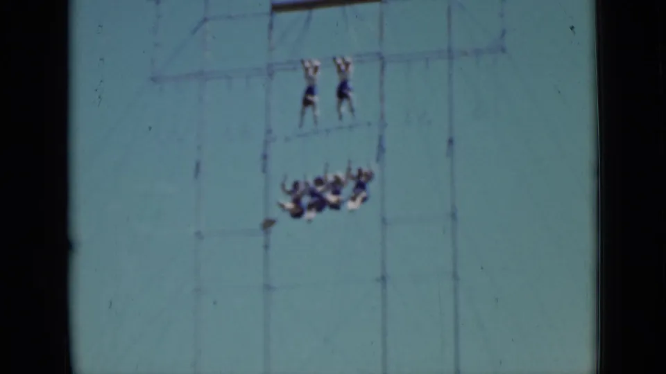 1937 San Francisco home-movie frame showing distant circus performers on tall aerial rigging, with two figures above and a group below.