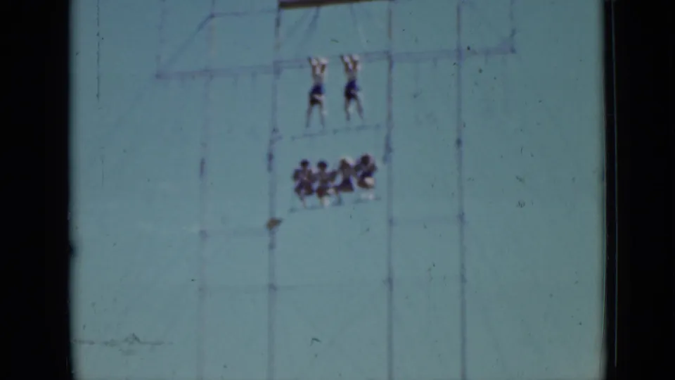 Distant 1937 San Francisco circus training view with two performers suspended above a clustered group on aerial apparatus.