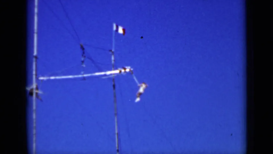 A lone circus performer appears to swing near a high horizontal bar in 1937 San Francisco home-movie footage, with rigging and a small flag visible.